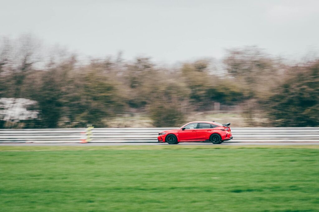 Dynamic capture of a red Honda Civic Type R speeding on Blyton track, showcasing automotive power.