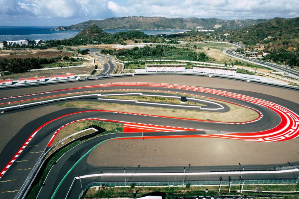 A stunning aerial shot of the Mandalika Circuit in Lombok, Indonesia, showcasing ocean and mountainous backdrop.