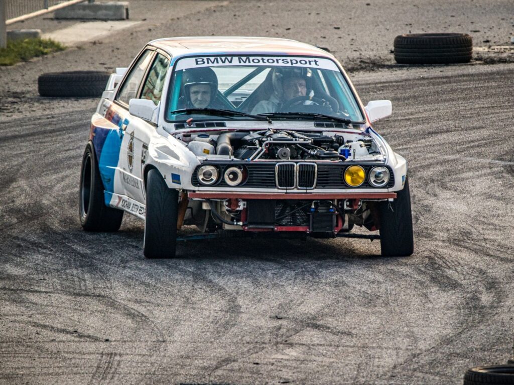 Front-facing view of a modified BMW Motorsport car racing on an asphalt track.