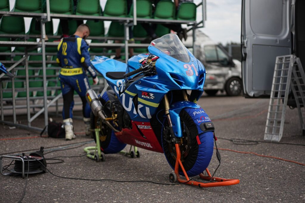 Close-up of a Suzuki motorcycle being prepped by a team for a race.