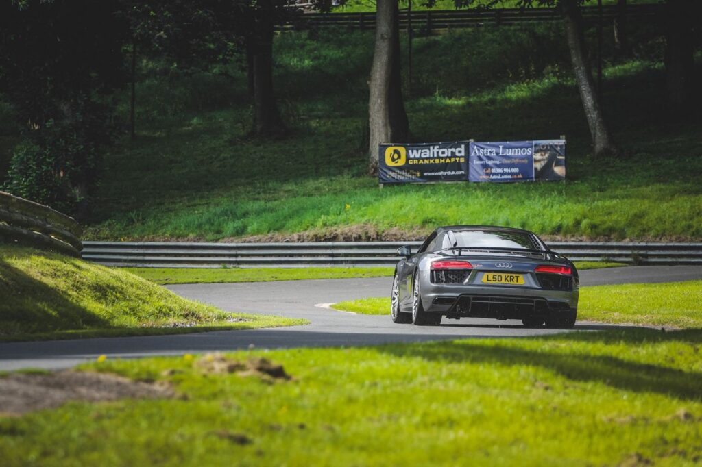 A luxury sports car navigating a scenic racetrack in a lush green setting.
