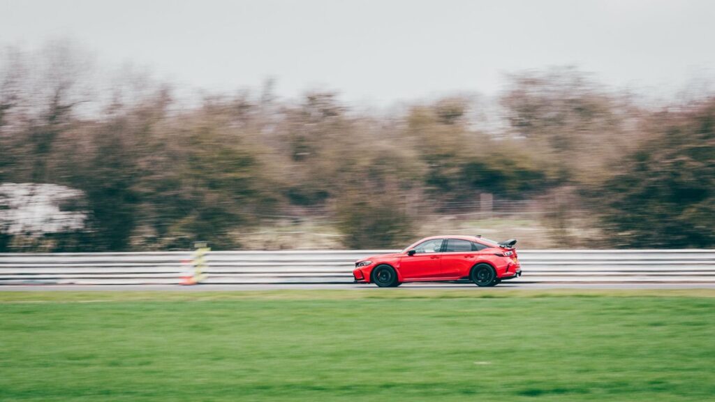 Dynamic capture of a red Honda Civic Type R speeding on Blyton track, showcasing automotive power.